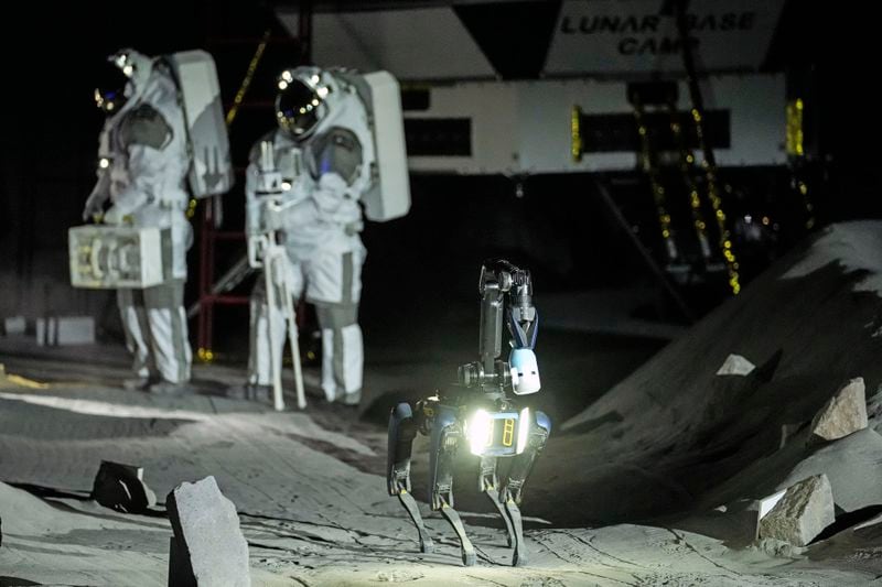 Astronauts Thomas Pesquet of France and Matthias Maurer of Germany and their canine-like robot demonstrate their training in lunar surface simulating conditions for future moon missions, like the Artemis lunar exploration program led by NASA, at the opening of the new LUNA facility at the European Astronaut Center in Cologne, Germany, Wednesday, Sept. 25, 2024. (AP Photo/Martin Meissner)