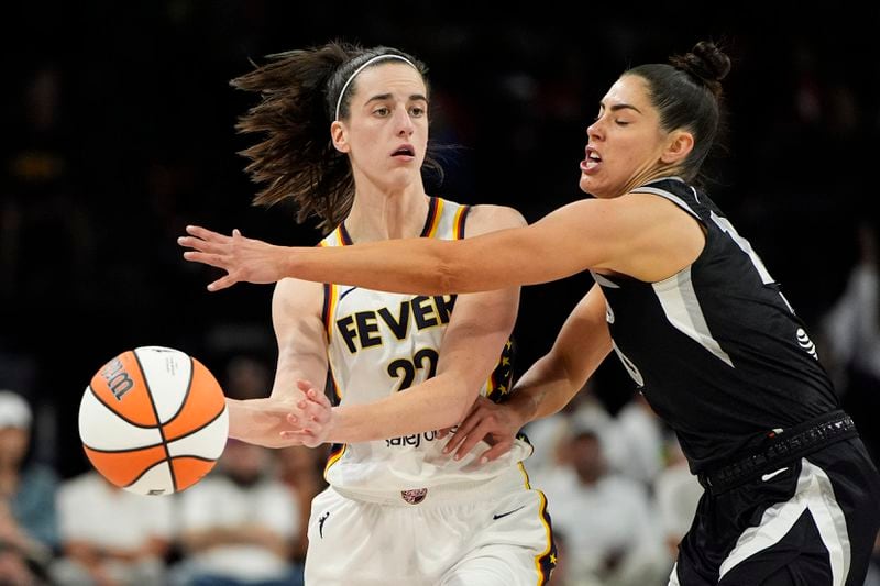 Indiana Fever guard Caitlin Clark (22) passes around Las Vegas Aces guard Kelsey Plum during the second half of a WNBA basketball game Saturday, May 25, 2024, in Las Vegas. (AP Photo/John Locher)