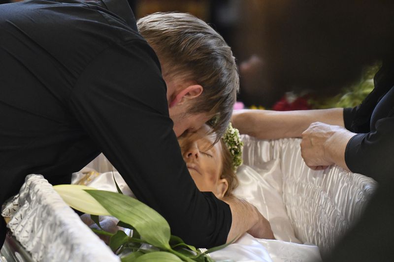 Yaroslav Bazylevych mourns over the coffins of his family members during the funeral service in the Garrison Church in Lviv, Ukraine, Friday, Sept. 6, 2024. Bazylevych's wife Yevgenia and their three daughters - Darina, 18, Emilia, 7, and Yaryna, 21 - were killed in Wednesday's Russian missile attack. (AP Photo/Mykola Tys)