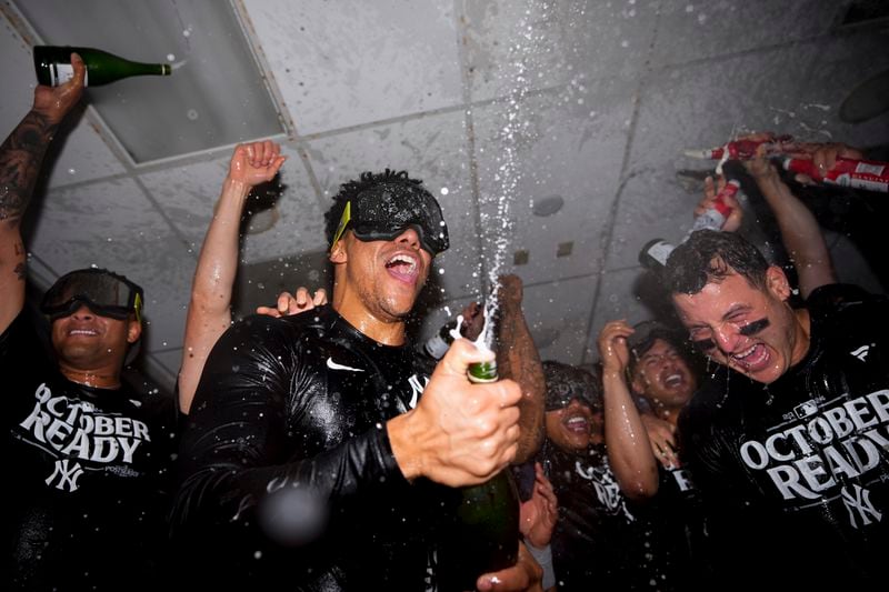 New York Yankees right fielder Juan Soto, center, celebrates clinching a playoff spot with teammates, including first baseman Anthony Rizzo, right, after a 2-1 win in 10 innings over the Seattle Mariners in a baseball game Wednesday, Sept. 18, 2024, in Seattle. (AP Photo/Lindsey Wasson)