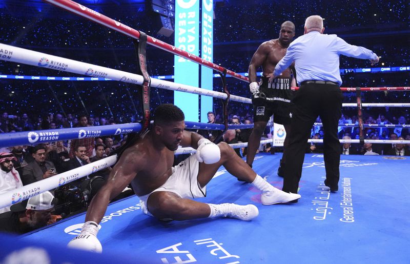 Anthony Joshua, left, knocked down by Daniel Dubois in the IBF World Heavyweight bout at Wembley Stadium, in London, Saturday, Sept. 21, 2024. (Bradley Collyer/PA via AP)