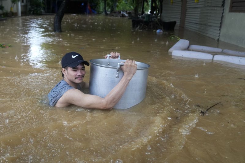 A resident uses a large pot to keep him afloat as he negotiates a flooded street caused by heavy rains from Tropical Storm Yagi, locally called Enteng, in Cainta, Rizal province, Philippines, Monday, Sept. 2, 2024. (AP Photo/Aaron Favila)