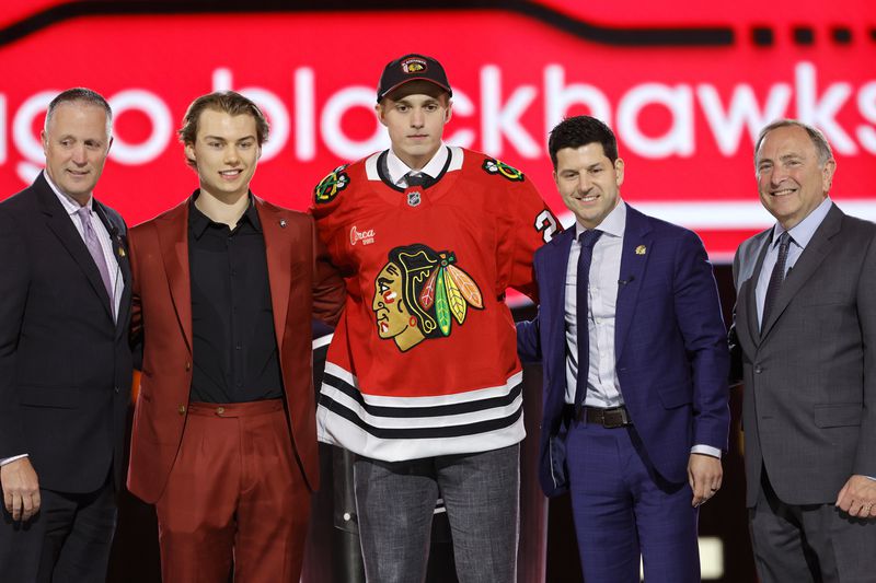 Artyom Levshunov, center, poses after being selected by the Chicago Blackhawks during the first round of the NHL hockey draft Friday, June 28, 2024, in Las Vegas. (AP Photo/Steve Marcus)