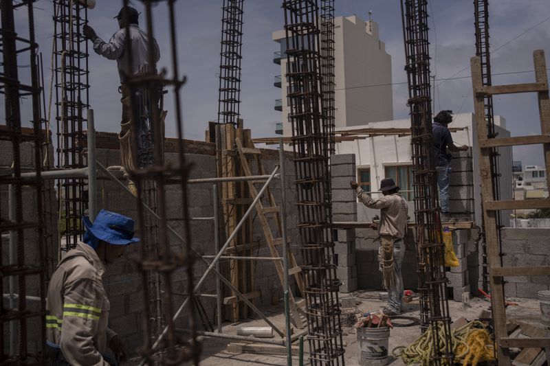 Construction workers carry out their tasks amid high temperatures in Veracruz, Mexico, Monday, June 17, 2024. Victims in Veracruz have made up nearly a third of Mexico's heat-related deaths as temperatures have reached 100 degrees in the humid Mexican gulf state. (AP Photo/Felix Marquez)