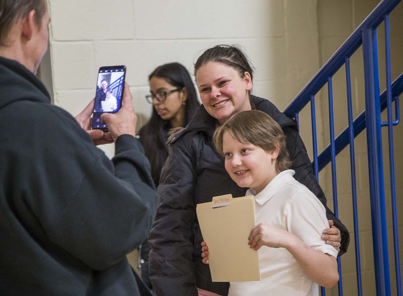 Jason Highsmith (left) takes a photo of his son, Harper-Archer Elementary 4th grader Gavin Highsmith (right) and his wife, Jessica Fullington (center), after Gavin received an award for most improved in math during the school's first awards ceremony, Friday, January 24, 2020. (ALYSSA POINTER/ALYSSA.POINTER@AJC.COM)