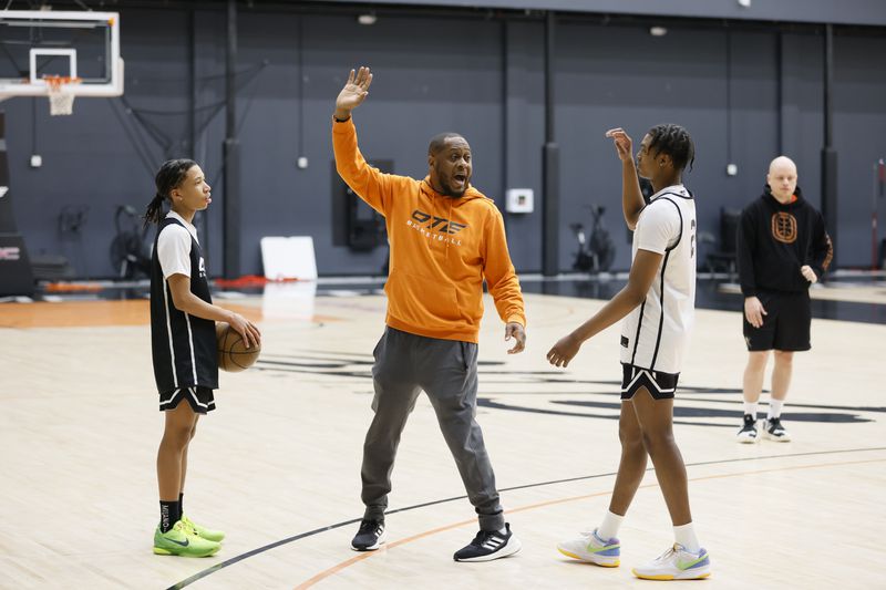 Coach Corey Frazier (center) gives directions to Jayden Wilkins (right) during a training session at Overtime Elite Arena on Monday, Nov. 6, 2023. (Miguel Martinez /miguel.martinezjimenez@ajc.com)