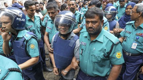 Police officers escort Shakil Ahmed, Ekattor television's former head of news, center, and its former chief correspondent Farzana Rupa, rear right in helmet, to the court of the Chief Metropolitan Magistrate in Dhaka, Bangladesh, Thursday, Aug. 22, 2024. (AP Photo)