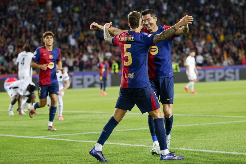 Barcelona's Robert Lewandowski, right, celebrates after scoring his side's fourth goal during the Champions League soccer match between Barcelona and Young Boys at the Lluis Companys Olympic Stadium in Barcelona, Spain, Tuesday, Oct. 1, 2024. (AP Photo/Joan Monfort)