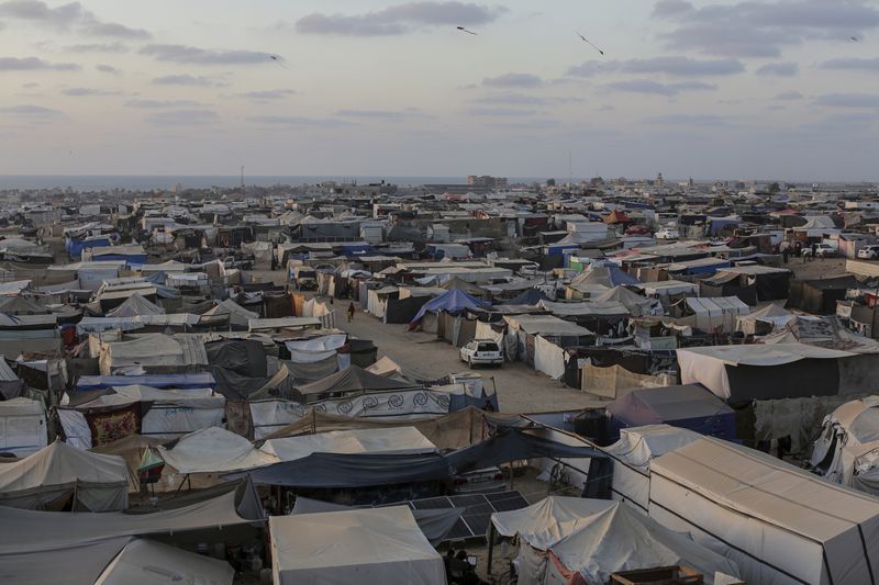 Palestinians displaced by the Israeli air and ground offensive on the Gaza Strip walk through a makeshift tent camp in Khan Younis, Gaza, Tuesday, June 18, 2024. (AP Photo/Jehad Alshrafi)