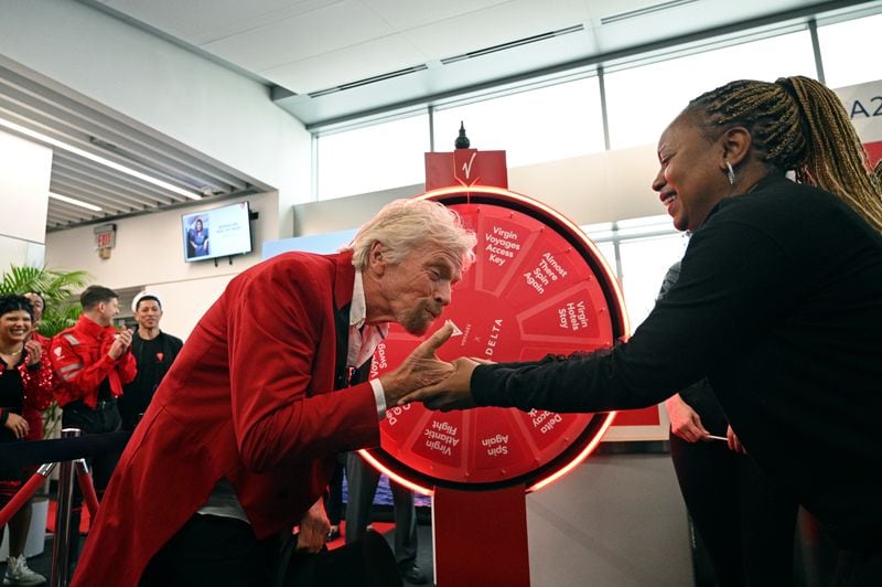 Richard Branson, founder of the Virgin Group, kisses customer Nekita Harvey’s hand as Virgin Voyages and Delta host a full departure gate takeover prior to the flight's boarding at Hartsfield-Jackson Atlanta International Airport, Thursday, Feb. 29, 2024, in Atlanta. Sir Richard Branson, Delta Air Lines and Virgin Voyages surprised customers on Delta Flight 1946 (from ATL to SJU), gifting all an-board a free cruise to celebrate all-new itineraries and the brand’s growing presence in San Juan later this year. (Hyosub Shin / Hyosub.Shin@ajc.com)