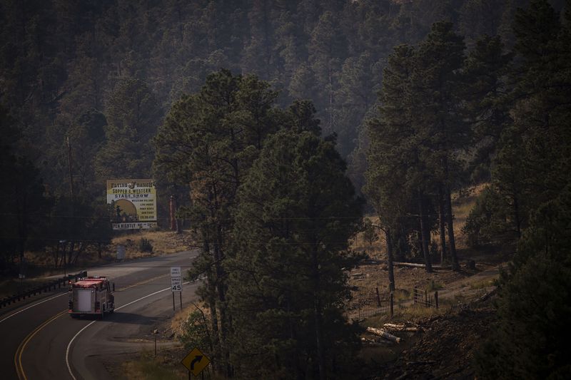 A fire truck drives on New Mexico State Road 48 towards the South Fork Fire near Ruidoso, N.M., on Tuesday, June 18, 2024. The South Fork Fire has consumed nearly 14,000 acres, according to a New Mexico State Forestry Division news release. (Chancey Bush/The Albuquerque Journal via AP)