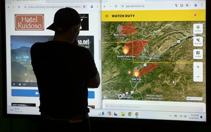 A Ruidoso resident checks a map on a screen while spending the night at a shelter in Roswell, N.M., Tuesday, June 18, 2024. Thousands of southern New Mexico residents fled the mountainous village as a wind-whipped wildfire tore through homes and other buildings. (AP Photo/Andres Leighton)