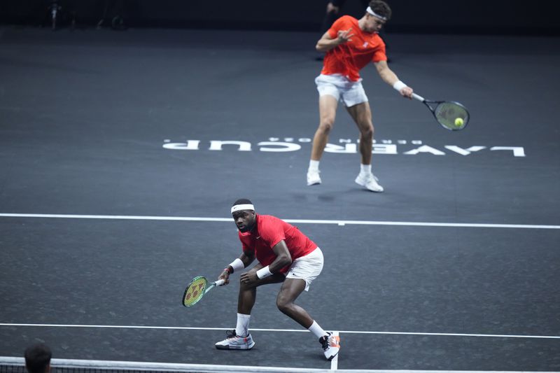 Team World's Frances Tiafoe, front, and Ben Shelton return the ball during their doubles match against Team Europe's Carlos Alcaraz and Casper Ruud on the third day of the Laver Cup tennis tournament, at the Uber arena in Berlin, Germany, Sunday, Sept. 22, 2024. (AP Photo/Ebrahim Noroozi)