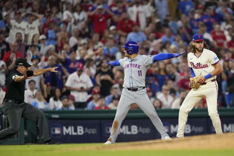 New York Mets' Jose Iglesias reacts past Philadelphia Phillies third base Alec Bohm after making it safely to third on a run scoring single by New York Mets' J.D. Martinez during the eighth inning of Game 1 of a baseball NL Division Series, Saturday, Oct. 5, 2024, in Philadelphia. (AP Photo/Matt Slocum)