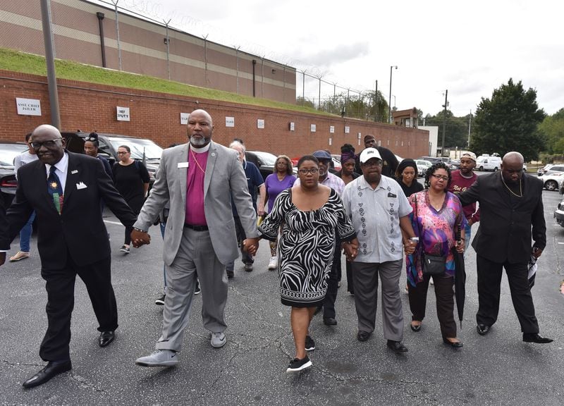 October, 2018 Atlanta - Tamara Cotman (center), who convicted in the Atlanta Public Schools test-cheating case, holding hands with Marietta Councilman Reggie Copeland (center left) and Rev. Timothy McDonald (center right) as she turns herself in at the Fulton County Jail in Atlanta on Tuesday, October 9, 2018. Tamara Cotman and Angela Williamson, who were convicted in 2015 of racketeering in the Atlanta Public Schools test-cheating case, turned themselves in at the Fulton County Jail. HYOSUB SHIN / HSHIN@AJC.COM