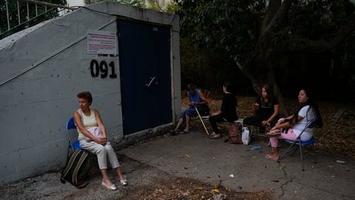 Israelis sit next to a public bomb shelter to stay safe from rockets fired from Lebanon, in Haifa, northern Israel, on Tuesday, Sept. 24, 2024. (AP Photo/Baz Ratner)