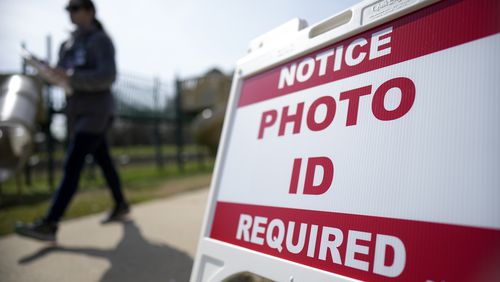 FILE - A Super Tuesday voter walks past a sign requiring a photo ID at a polling location, March 5, 2024, in Mount Holly, N.C. (AP Photo/Chris Carlson, File)