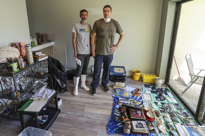 Miles Runner, left, and his brother Chris pause while cleaning out the home of their mother Donna Fagersten who died from flooding in Hurricane Helene on Wednesday, Oct. 2, 2024, in Indian Rocks Beach, Fla. (AP Photo/Mike Carlson)