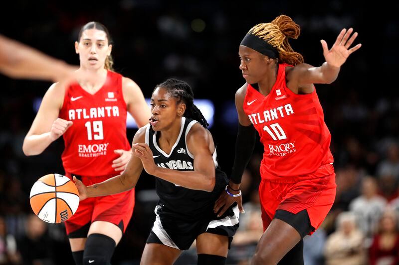 Las Vegas Aces guard Tiffany Hayes, center, takes the ball upcourt between Atlanta Dream forward Lorela Cubaj (19) and guard Rhyne Howard (10) during the first half of a WNBA basketball game Friday, Aug. 30, 2024, in Las Vegas. (Steve Marcus/Las Vegas Sun via AP)