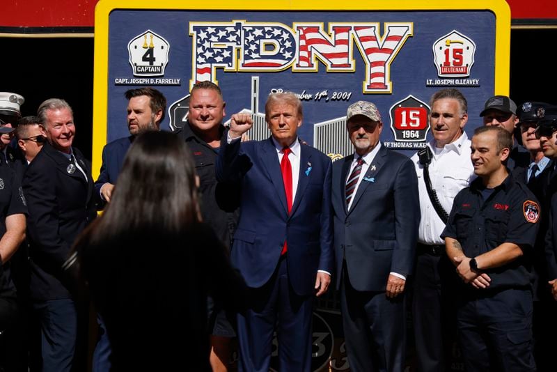 Republican presidential nominee former President Donald Trump, center and Republican vice presidential nominee Sen. JD Vance, R-Ohio, pose for a photo with firefighters from Engine 4 Ladder 15 on the 23rd anniversary of the Sept. 11, 2001 terror attacks, Wednesday, Sept. 11, 2024, in New York. (AP Photo/Stefan Jeremiah)