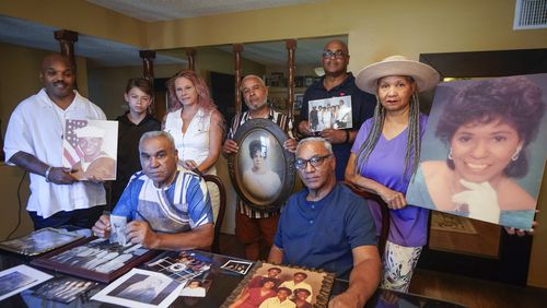 Descendants of Nelson Bell, brothers Milford Fonza, front left, and Elmer Fonza, front right, surrounded by extended family members, show their ancestors' pictures in Glendora, Calif., on Friday, Sept. 8, 2023. Family members standing from left: Trent Mure, with son Armani Mure, and his wife Tami Mure, William Woolery, Louie Hobbs and Carolyn Fonza. (AP Photo/Damian Dovarganes)