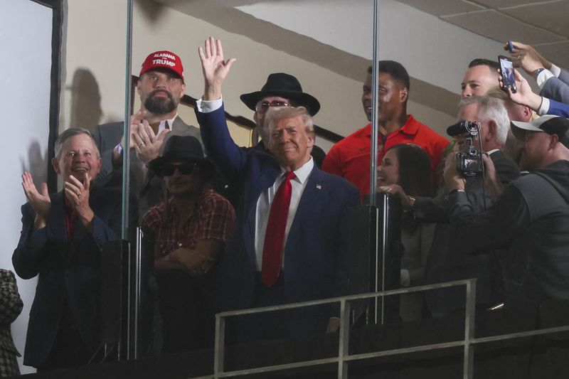 Former President Donald Trump waves to the crowd attending the football game between Alabama and Georgia in Tuscaloosa on Saturday.