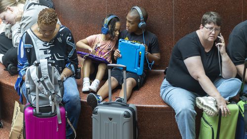 Travelers pass the time at Hartsfield-Jackson Atlanta International Airport after hundreds of airline flights were canceled due to a global technology outage Friday.    (Steve Schaefer / AJC)  (Steve Schaefer / AJC)