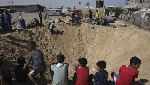 Palestinian children sit at the edge of a crater after an Israeli airstrike in Khan Younis, southern Gaza Strip, Friday, June 21, 2024. (AP Photo /Jehad Alshrafi)