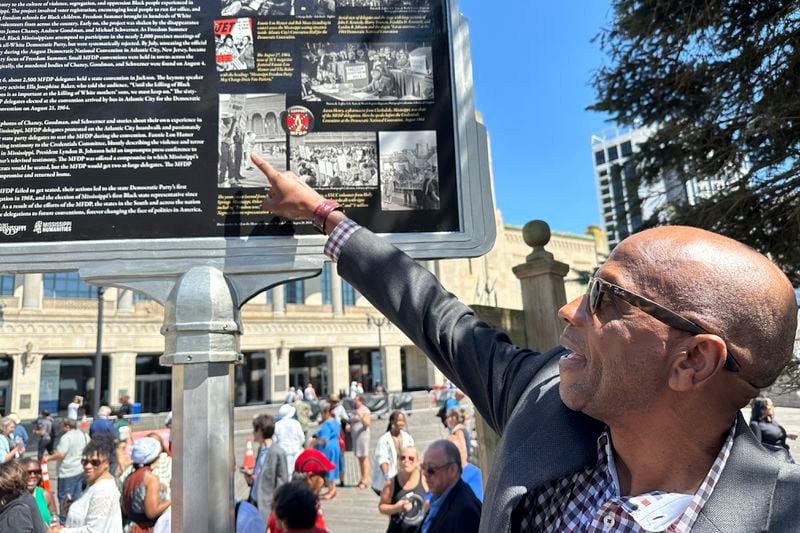 Roy DeBerry of the Student Nonviolent Coordinating Committee points to a photo of himself as a teenager on the newly unveiled Mississippi Freedom Trail marker on the boardwalk in Atlantic City, N.J., Tuesday, August 20, 2024. DeBerry was part of a racially-integrated group protesting the seating of an all-white Mississippi delegation to the 1964 Democratic National Convention at the location. (AP Photo/Ted Shaffrey)