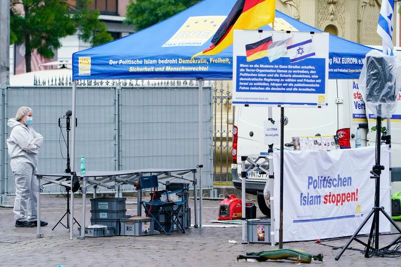 A forensic police officers walks past a smashed stall of Pax Europa which had a banner with writing reading "Stop political Islam", on the market square in Mannheim, Germany, Friday, May 31, 2024. An assailant with a knife attacked and wounded several people in a central square in the southwestern German city of Mannheim on Friday, police said. Police shot the attacker, who also was hurt. Pax Europa, which describes itself as an organization that informs the public about the dangers posed by the “increasing spread and influence of political Islam,” said that the attack happened on the sidelines of an event it organized. It said that Michael Stürzenberger, an anti-Islam activist who has spoken at its events. was among those wounded. (Uwe Anspach/dpa via AP)