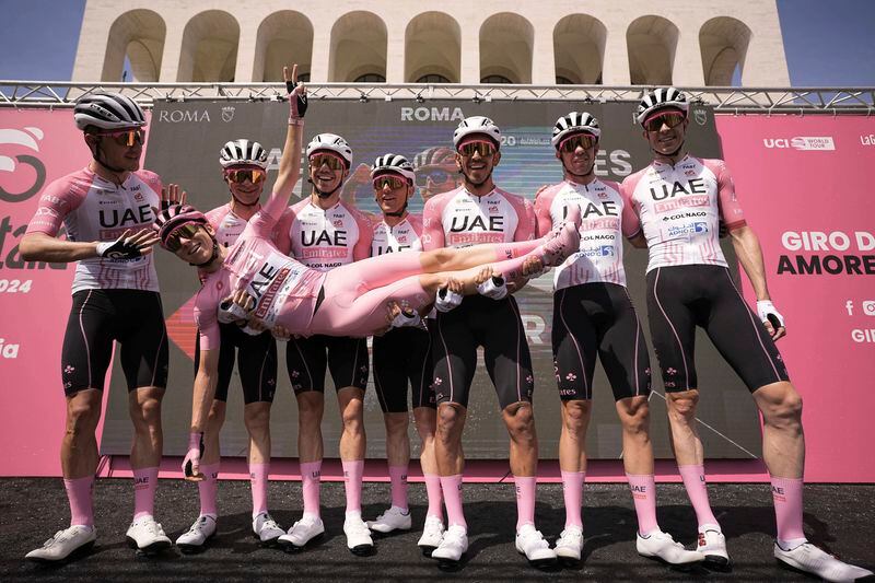 Slovenia's Tadej Pogacar, wearing the pink jersey of the race overall leader, is lifted in celebration by teammates ahead of the start of the final stage of the Giro d'Italia cycling race, in front of the Palazzo della Civilta' Italiana, also known as Colosseo Quadrato (Square Colosseum) in Rome, Sunday, May 26, 2024. (Marco Alpozzi/LaPresse via AP)