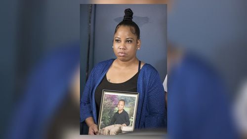 Allison Woods holds a photo of her son Isaiah Payton. The 12-year-old was shot after a football game in August and remains hospitalized. Doctors say he likely won't walk again.