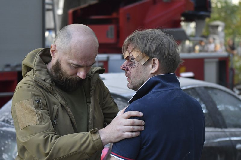 A man helps to a wounded man near an apartment building destroyed by Russian missile attack in centre Lviv, Western Ukraine, Wednesday Sept. 4, 2024. (AP Photo/Mykola Tys)