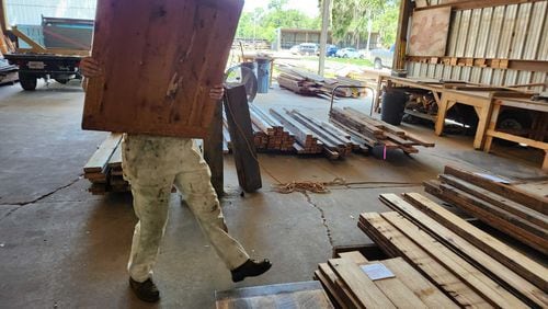 Re:Purpose Savannah salvage manager Jordan Lynch carries a donated wood panel into the organization's warehouse, where they get salvaged materials like this ready for reuse in other projects. (Photo Courtesy of Emily Jones/WABE)