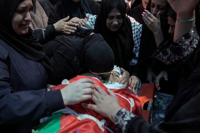 Relatives of Muhammad Sarhan,15, mourn around his body, draped in the Palestinian flag, during his funeral in the West Bank town of Tulkarem, Tuesday, July 2, 2024. Palestinian health officials say Sarhan and another woman were shot and killed, and four people were wounded by Israeli forces during a raid in the northern West Bank on Monday. (AP Photo/Majdi Mohammed)