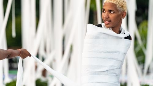 Incoming senior Jayden Coleman stands wrapped in toilet paper in the parking lot at Marietta High School in Marietta on Wednesday, July 31, 2024. (Seeger Gray / AJC)