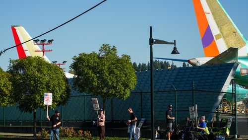 Boeing 737 Max aircrafts are seen behind fences as Boeing employees work the picket line while striking Tuesday, Sept. 24, 2024, next to the company's facilities in Renton, Wash. (AP Photo/Lindsey Wasson)