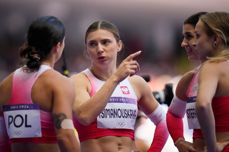 FILE – Former Belarusian athlete Krystsina Tsimanouskaya, who sought political asylum in Poland three years ago, talks with teammates following their women's 4x100-meter relay heat at the Paris Olympics, on Aug. 8, 2024, in Saint-Denis, France. (AP Photo/Petr David Josek, File)