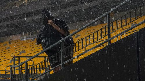 A spectator stands under driving range during a weather delay prior to an NFL football game between the Pittsburgh Steelers and the Dallas Cowboys, Sunday, Oct. 6, 2024, in Pittsburgh. (AP Photo/Matt Freed)