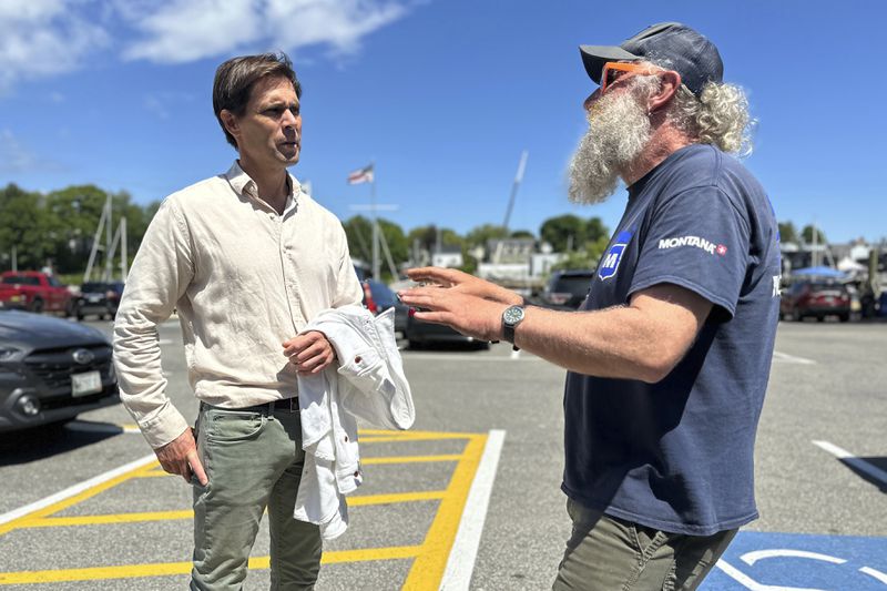 Tom Hedstrom, chair of the Select Board, speaks with schooner captain Aaron Lincoln during a visit to the harbor, Tuesday, June 4, 2024, in Camden, Maine. Hedstrom said residents were united in their anger over one homeowner's poisoning of a neighbor's trees to gain a view, especially due to the proximity of the water. (AP Photo/Robert F. Bukaty)