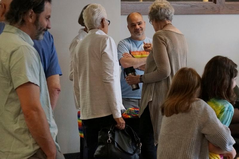 Ryan Hanish, center, talks with other congregants at the "Reconciling in Christ" booth during a ministry fair at Transfiguration Lutheran Church in Bloomington, Minn, on Sept. 8, 2024. The group affirms the church's mission of inclusion for LGBTQ+ people. (AP Photo/Giovanna Dell'Orto)