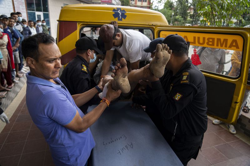 An injured man is brought for treatment at a hospital, after a bus carrying Indian tourists fell into a river near Abukhaireni town about 75 miles west of the capital Kathmandu, Nepal, Friday, Aug. 23, 2024. (AP Photo/Niranjan Shrestha)