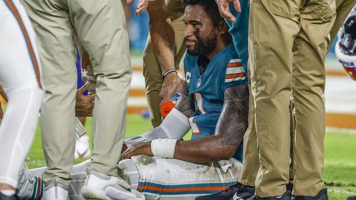 Miami Dolphins head coach Mike McDaniel talks to quarterback Tua Tagovailoa (1) as he leaves the game after suffering a concussion during the second half of an NFL football game against the Buffalo Bills, Thursday, Sept. 12, 2024, in Miami Gardens, Fla. (AP Photo/Rebecca Blackwell)