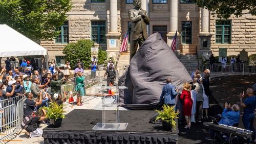 Dignitaries pull the cover off the statue honoring the late civil rights leader and congressman John Lewis during its unveiling ceremony in Decatur, Ga., on Saturday, Aug 24, 2024. (Steve Schaefer/Atlanta Journal-Constitution via AP)