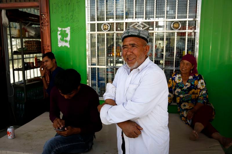 FILE - Muzitohtahon, center, an Uyghur farmer in his early seventies who moved to the village three years ago, said he is no longer a Muslim, stands outside a convenience store at the Unity New Village in Hotan, in western China's Xinjiang region on Sept. 21, 2018. Authorities in China's western Xinjiang region have been systematically replacing the names of villages inhabited by Uyghurs and other ethnic minorities to reflect the ruling Communist Party's ideology, as part of an attack on their cultural identity, according to a report released Wednesday, June 19, 2024, by Human Rights Watch. (AP Photo/Andy Wong, File)