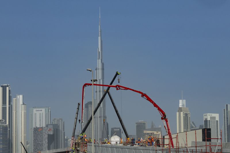 With Burj Khalifa, world's tallest tower in background, laborers work at a construction site in Dubai, United Arab Emirates, Tuesday, Aug. 13, 2024. (AP Photo/Altaf Qadri)