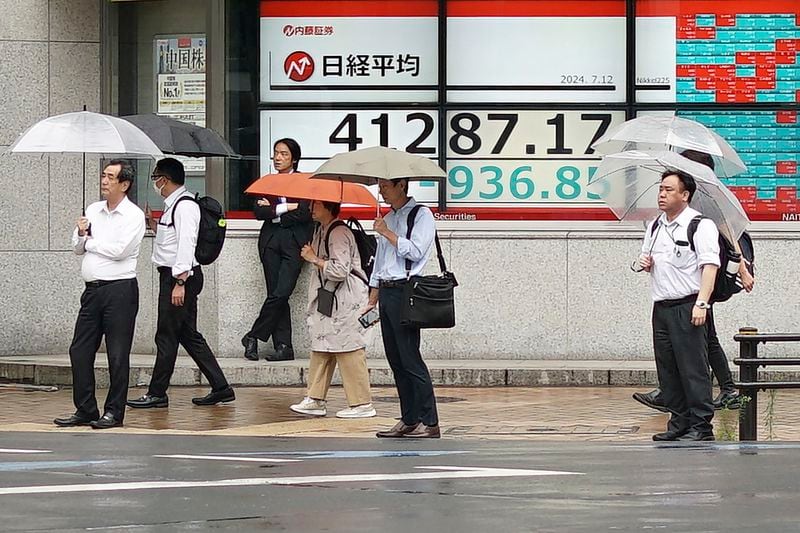 People walk in front of an electronic stock board showing Japan's Nikkei index at a securities firm Friday, July 12, 2024, in Tokyo. (AP Photo/Eugene Hoshiko)