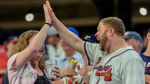 Fans high five after the singing of America the Beautiful in the seventh inning of a baseball game between the Los Angeles Dodgers and the Atlanta Braves, Sunday, Sept. 15, 2024, in Atlanta. (AP Photo/Jason Allen)