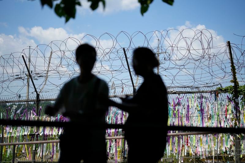 Visitors walk near a wire fence decorated with ribbons written with messages wishing for the reunification of the two Koreas at the Imjingak Pavilion in Paju, South Korea, Wednesday, June 26, 2024. A suspected hypersonic missile launched by North Korea exploded in flight on Wednesday, South Korea's military said, a development that comes as North Korea is protesting the regional deployment of a U.S. aircraft carrier for a trilateral military drill with South Korea and Japan. (AP Photo/Lee Jin-man)