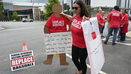 Jennifer Susko, one of the organizers of the "Replace Ragsdale" rally, holds a life-sized sign that a Cobb County teacher made and sent because the teacher was too afraid to attend the rally at the Cobb County School District building, Thursday, Sept. 14, 2023, in Marietta, in person. The school district's response to such actions has drawn criticism. (Hyosub Shin / Hyosub.Shin@ajc.com)